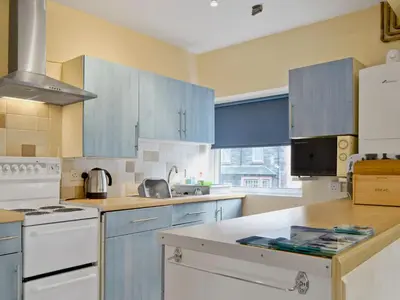 a kitchen with blue cabinets and white appliances at Serendipity in Keswick