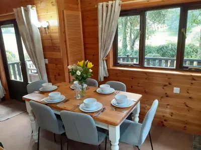 a dining room with a table and chairs and windows at Ewe How - Burnside Park in Keswick