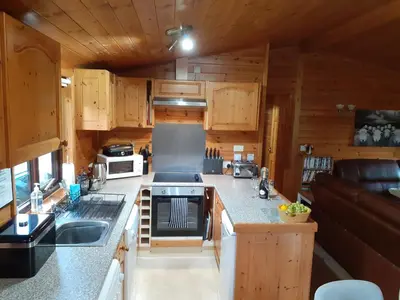 a kitchen with wooden cabinets and a stove top oven at Ewe How - Burnside Park in Keswick
