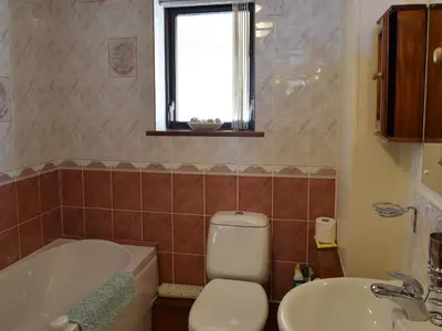 a bathroom with a toilet and a tub and a sink at Dairy Lodge in Keswick