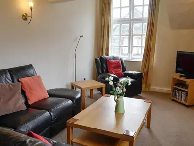 a living room with couches and a table with a vase of flowers at Bay Tree in Keswick
