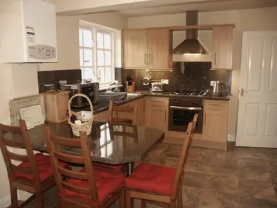 a kitchen with a table and chairs and a stove at Bay Tree in Keswick