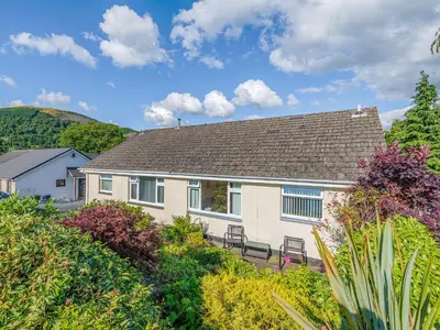a white house with a bench in front of it at Blencathra Bank in Keswick