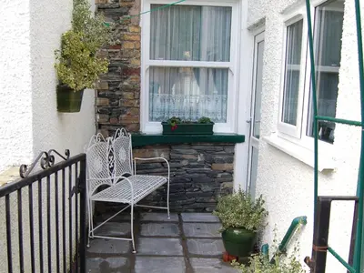 a patio with two chairs and a window at Millie's Cottage in Keswick