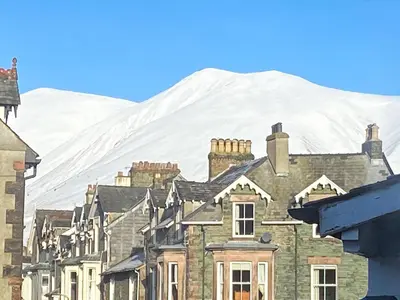 a painting of a town with a snow covered mountain in the background at Kingstarn in Keswick