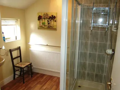 a bathroom with a shower with a chair and a table at Kingstarn in Keswick