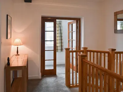a hallway with a wooden door and a stairway at Acorn Lodge Cottage in Keswick