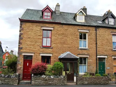 an old brick house with red doors and windows at The Ivy Cottage in Keswick
