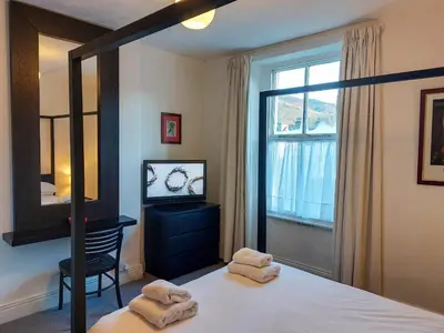 a bedroom with a bed and a mirror and a window at The Ivy Cottage in Keswick