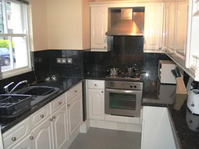 a kitchen with white cabinets and a sink and a stove at Helvellyn House Apartment in Keswick