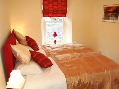 a bedroom with a bed with pillows and a window at 3 The Hollies in Keswick