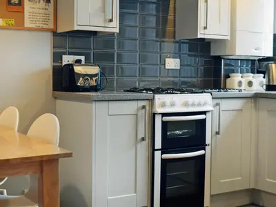 a kitchen with white cabinets and a stove top oven at Wickhams View in Keswick