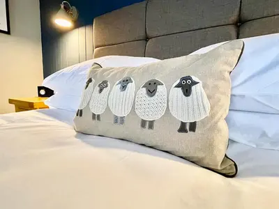 a pillow with a group of sheep on a bed at High Style Apartment in Keswick