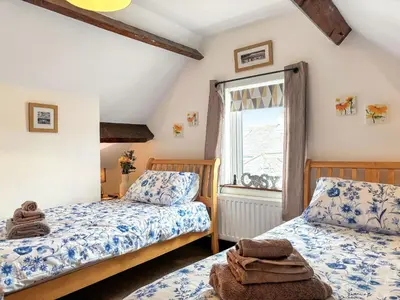 a bedroom with two beds and a window at Lavender Cottage in Keswick