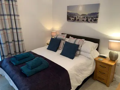 a bedroom with a large bed with blue pillows at 2 Windsor House in Keswick
