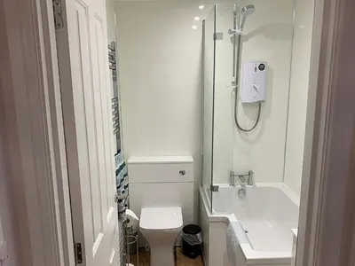 a white bathroom with a toilet and a sink at 2 Windsor House in Keswick