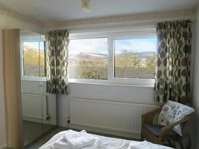 a bedroom with a bed and two windows with a view at Peel Wyke in Keswick
