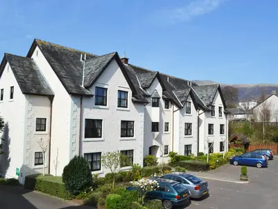 a row of white houses with cars parked in a parking lot at Limetrees in Keswick
