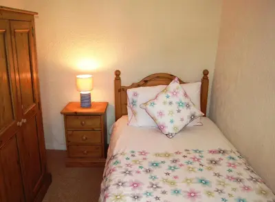 a bed with pillows and a lamp on a night stand at Laal Yan in Keswick
