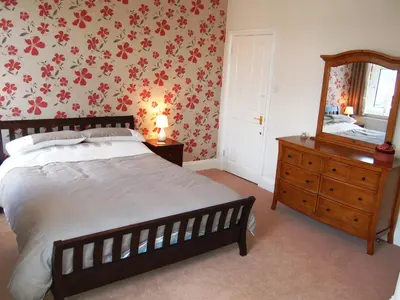 a bedroom with a bed and a dresser and a mirror at York House in Keswick