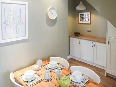 a dining room table with chairs and a clock on the wall at Hastings in Keswick