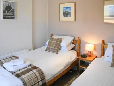a room with two beds and a lamp on a table at Hastings in Keswick