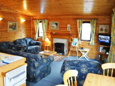 a living room with blue furniture and a fireplace at Glenmore Lodge in Keswick