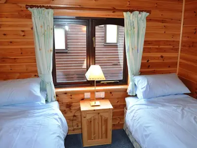 two beds in a log cabin with a window at Glenmore Lodge in Keswick