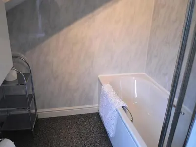 a bathroom with a bath tub with a shower at Uncle's Cottage in Keswick
