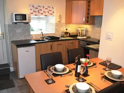a kitchen with a wooden table with chairs and a dining room at Uncle's Cottage in Keswick