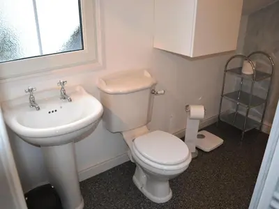 a bathroom with a white toilet and a sink at Uncle's Cottage in Keswick