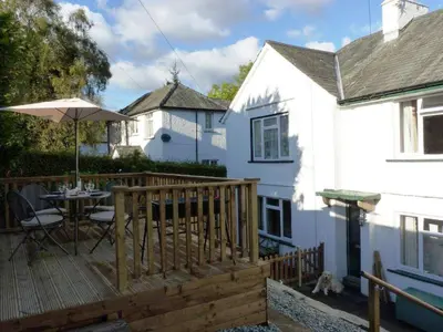 a wooden deck with a table and an umbrella at Riverbank in Keswick