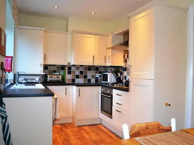 a kitchen with white cabinets and black counter tops at Riverbank in Keswick