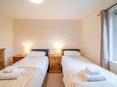 two twin beds in a room with a window at Barleycorn in Keswick
