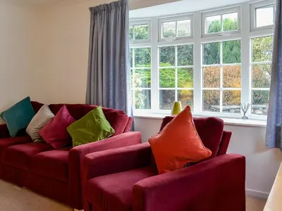two red chairs in a living room with windows at Haystacks in Keswick