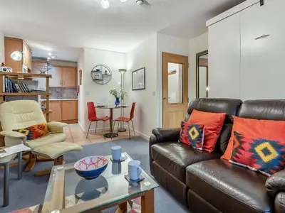 a living room with a leather couch and a table at Chaucer Lodge Apt 1 in Keswick