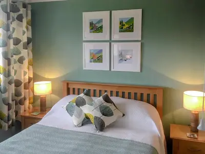 a bedroom with a bed with three pictures on the wall at The Bolthole Formerly Candlemas in Keswick