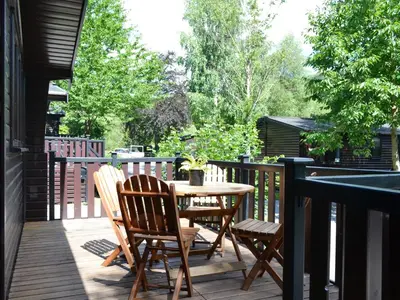 a patio with a table and chairs on a deck at Fern Lodge- Burnside Park in Keswick