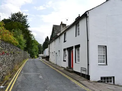 an empty street with white houses and a wall at 4 The Plosh in Keswick