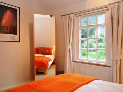 a mirror in a bedroom with a bed and a window at 4 The Plosh in Keswick