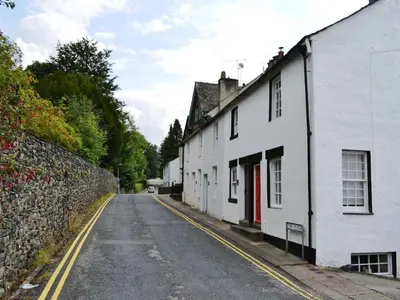 an empty street with white houses and a stone wall at 5 The Plosh in Keswick