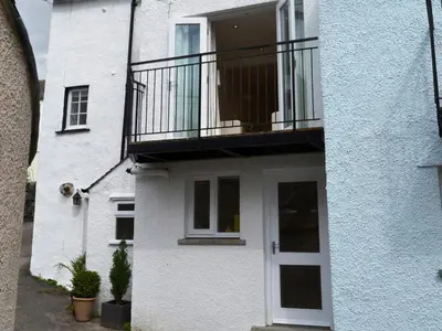 a white building with a balcony and a door at 5 The Plosh in Keswick