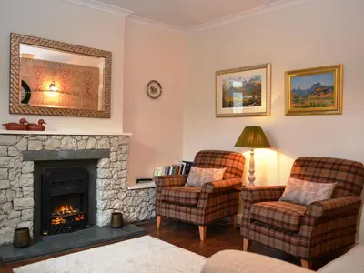 a living room with two chairs and a fireplace at Catbells Cottage Keswick in Keswick