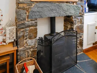 a stone fireplace with a black stove at 1 Tower Cottage in Portinscale