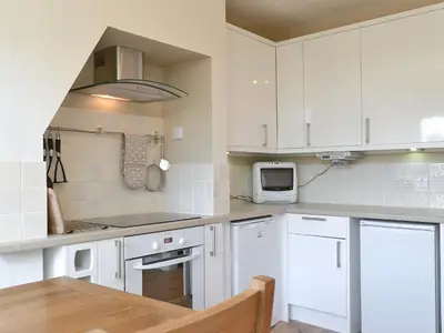 a kitchen with white cabinets and a wooden table at 14 Greta Villas in Keswick