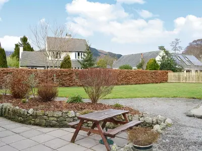 a wooden picnic table in a garden with a yard at La'al Gem in Keswick