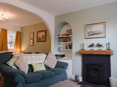 a living room with a blue couch and a fireplace at Poachers Cottage in Keswick