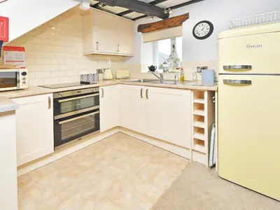 a kitchen with white cabinets and a refrigerator at Osprey Cottage in Bassenthwaite