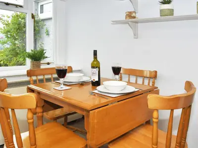 a dining room table with a bottle of wine and glasses at Osprey Cottage in Bassenthwaite