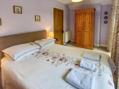 a bedroom with a large white bed with flowers on it at Oak Lea in Braithwaite